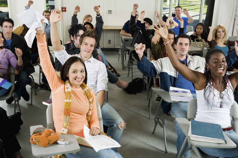 students in classroom raising hands 